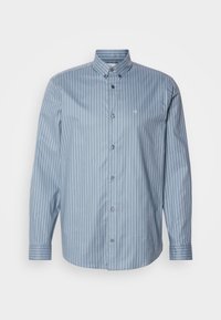 Chemise bleue à manches longues avec rayures verticales blanches et col boutonné, avec un petit logo « ck » sur la poitrine.