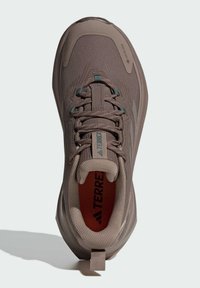 Brauner Sportschuh mit texturiertem Obermaterial, GORE-TEX-Branding, gepolstertem Schaft und einer lebhaften orangefarbenen Innensohle mit einer Schlaufe an der Ferse.