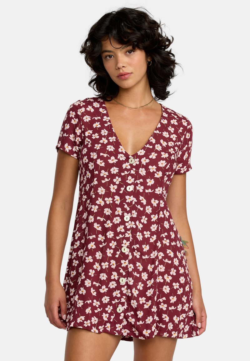 Robe florale bordeaux à manches courtes, décolleté en V profond et devant à boutons. Elle présente de petites fleurs blanches et roses et un tissu léger et texturé.