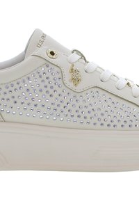 Bílé tenisky s hladkým koženým povrchem, na boku zdobené stříbrnými kamínky a zlatým logem. Obsahují tkaničky a polstrovaný límec.