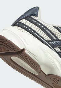 Atletická obuv s priedušným sieťovaným vrchom a tmavomodrými akcentmi, textúrovou bielou podrážkou a značením "CLOUDFOAM" na boku.