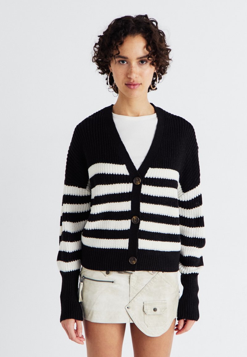 Black and white striped cardigan with a v-neck, button front, and ribbed texture. Long sleeves extend past the wrist with a fitted silhouette.