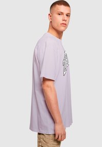 Levanduľové bavlnené tričko so voľným strihom, okrúhlym výstrihom a grafickým potlačou na prednej strane. Mäkšia textúra so short sleeves.