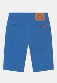 Modré denimové šortky s rovnýcm střihem, s kapsami vzadu, hnědou koženou etiketou a červeným logem na zadní kapse.