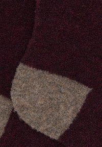 Calzini in misto lana con colori marrone scuro e beige. Presentano una superficie testurizzata con un motivo triangolare a contrasto nell'area delle dita.