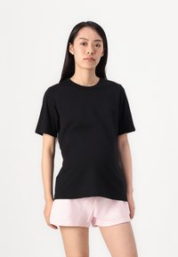 Black short-sleeve t-shirt made of cotton, featuring a round neckline and a relaxed fit, paired with light pink shorts.
