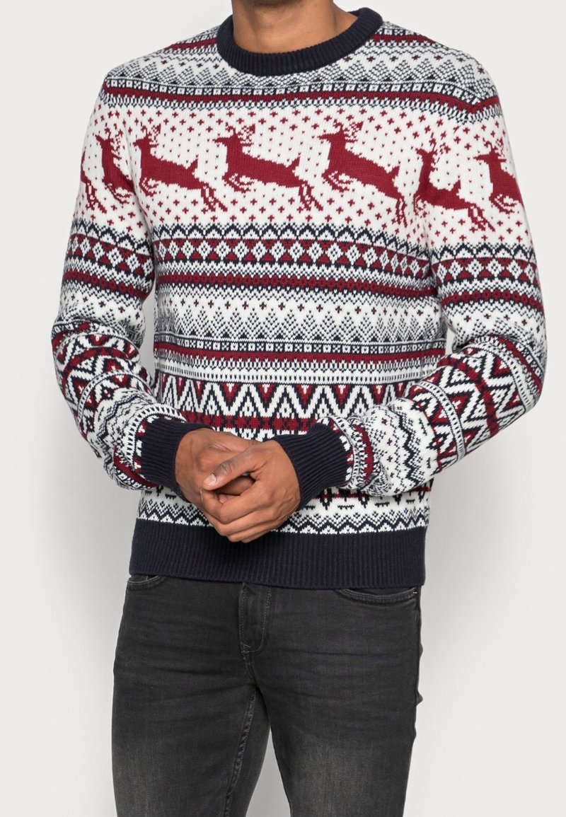 Röd- och vitstickad tröja med renmönster, med en marinblå rund halsringning och ribbade muddar och fåll, som visar geometriska mönster.