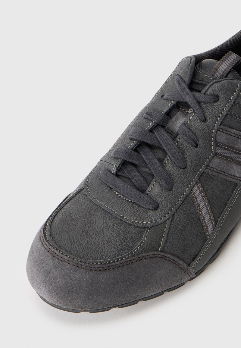 Sneaker grigio con tomaia in pelle texturizzata, punta in suede, cuciture a contrasto e lacci piatti. Presenta dettagli sintetici e suola in gomma.