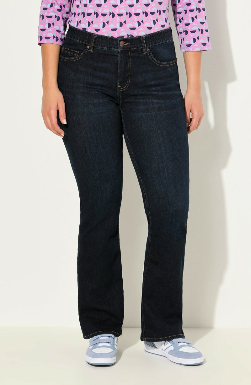 Mörkblå denim jeans med vid ben, fem fickor, sydda detaljer och knappstängning, kombinerat med en mönstrad rosa topp och blå sneakers.