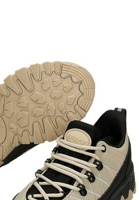 Buty outdoorowe w beżowo-czarnym wzorze, z siateczkowym górnym materiałem, solidną gumową podeszwą z teksturowanym bieżnikiem oraz pasującymi sznurowadłami.