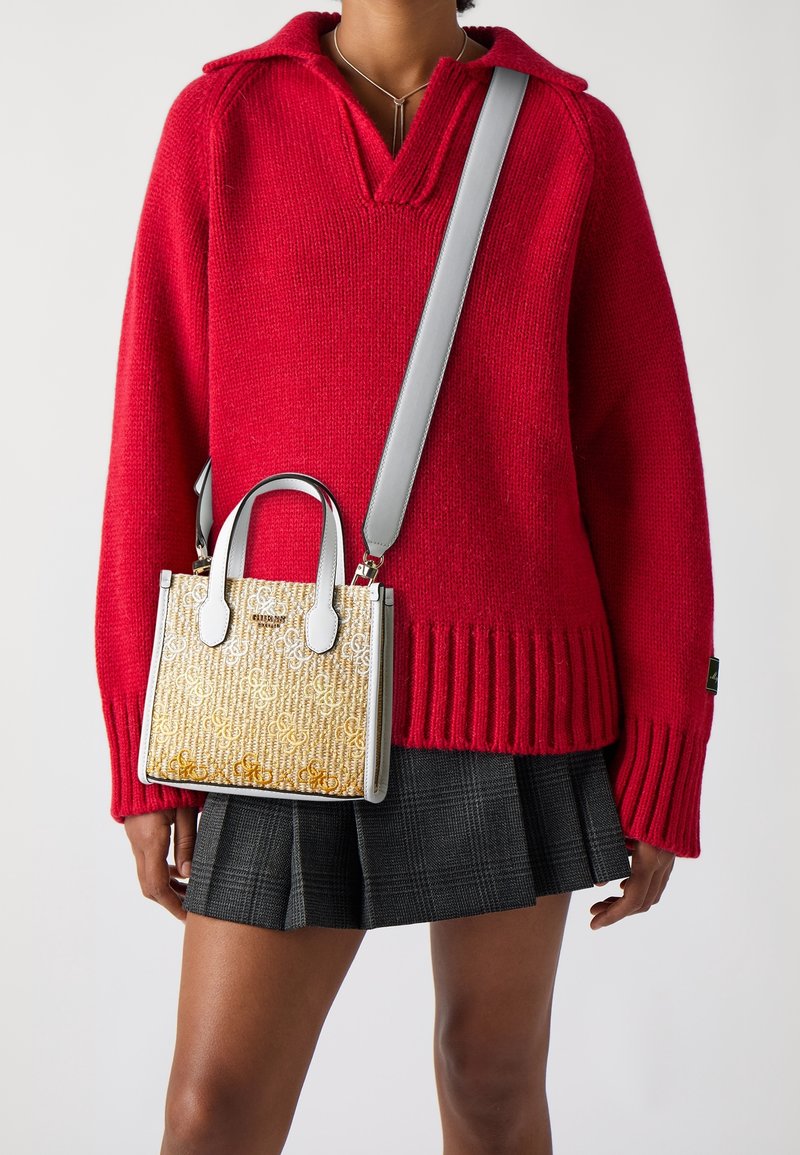 Pull tricot rouge avec col, accompagné d'un petit sac à main structuré or et blanc avec double poignées et une bandoulière amovible.