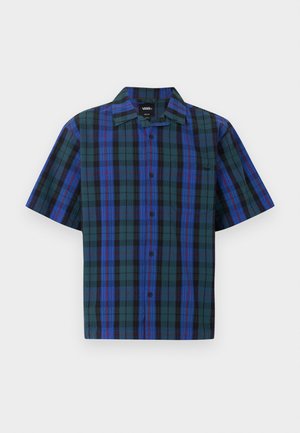 Chemise à manches courtes boutonnée avec un motif à carreaux verts, bleus et noirs et une petite poche poitrine sur fond blanc.