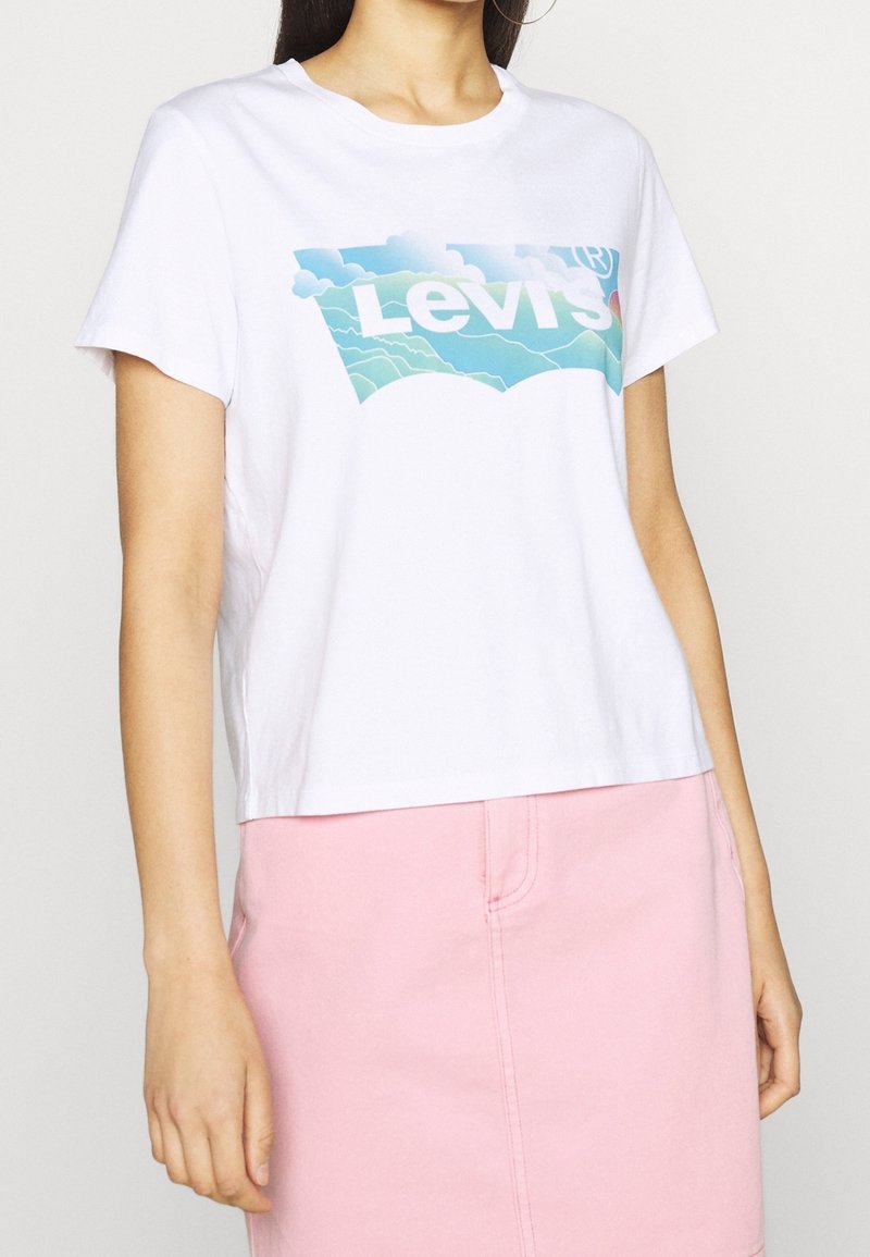 Vit bomull t-shirt med en cropped design, som har en blå grafisk Levi's-logotyp och ett molnmönster på framsidan.