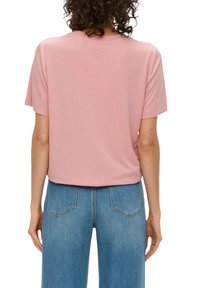 Roze T-shirt met korte mouwen, een relaxte pasvorm, zachte katoenen stof, ribbelkraag en rechte zoom, gecombineerd met lichtblauwe high-waisted jeans.