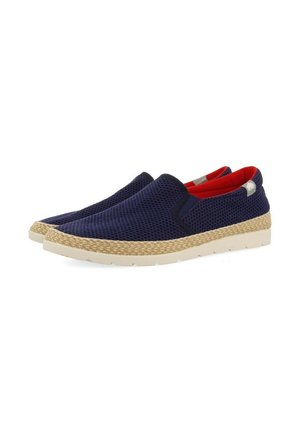 Zapatos tipo slip-on de malla azul marino con un interior rojo y acentos de yute trenzado. Cuentan con una suela de goma blanca y detalles de costura mínimos.