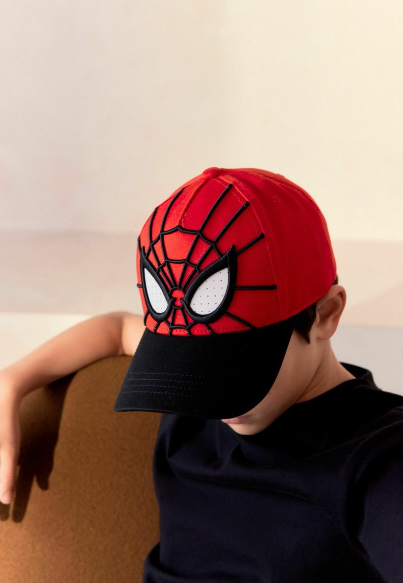 Gorra de béisbol roja con diseño de la cara de Spider-Man, con acentos negros, textura similar a malla y visera negra sólida, llevada por una persona.