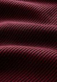 Burgundia triibuline kangas, millel on sile tekstuur ja vahelduvad vertikaalsed sooned, mis annavad materjalile sügavuse ja dimensiooni.