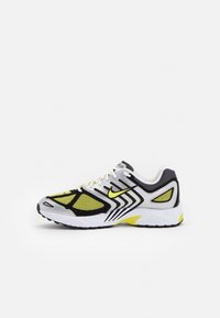 Sapatilha de corrida Nike com uma combinação de cores em preto, branco e amarelo neon. Apresenta material em malha, colarinho acolchoado e sola texturizada para melhor aderência.