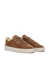 Sneaker in suede marrone con superficie texturizzata, lacci piatti, suole in gomma color crema e branding minimale sul lato.