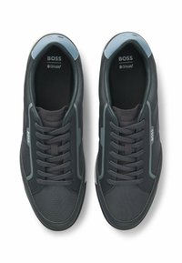 Tummanharmaat lenkkarit, jotka on valmistettu verkko- ja synteettisistä materiaaleista. Mukana pyöreät nauhat, vaaleansiniset pyöreät kantakoristeet ja hienovarainen brändäys.