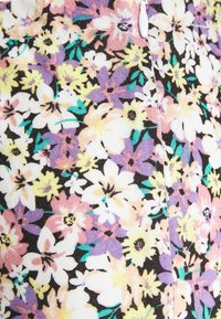 Tissu floral avec un mélange de fleurs blanches, jaunes, roses et violettes sur un fond noir ; tissage texturé avec des détails de couture visibles.