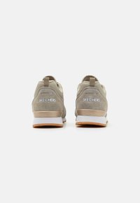 Beige athletic shoes with a smooth suede and mesh upper. Features a cushioned white midsole and rubber outsole. "SKECHERS" logo on heel.