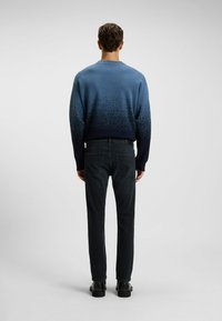 Suéter de punto con degradado azul y puños azul oscuro, combinado con jeans de mezclilla oscura y zapatos negros. El suéter cuenta con un acabado texturizado.