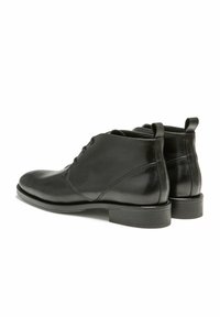Bottines en cuir noir avec une finition lisse, bout rond, lacets à l'avant et un petit talon carré. Comprend des languettes arrière doubles.