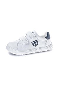 Zapatillas blancas para niños con dos tiras de Velcro, con un refuerzo en el talón de color azul marino y un logo bordado azul marino en el lateral, sobre un fondo blanco.