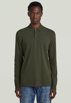 Polo a maniche lunghe in verde oliva scuro, realizzata in cotone. Presenta un colletto classico e una patta con due bottoni. Vestibilità casual con orlo dritto.