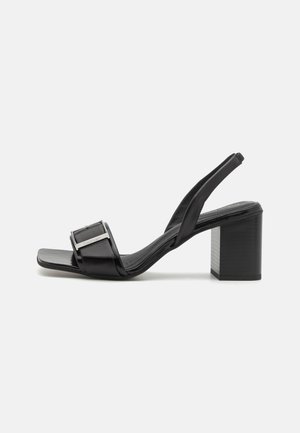 Schwarze Slingback-Sandale aus Leder mit Blockabsatz und quadratischer Spitze, mit silberner Schnallenakzent auf dem Vorderriemen.
