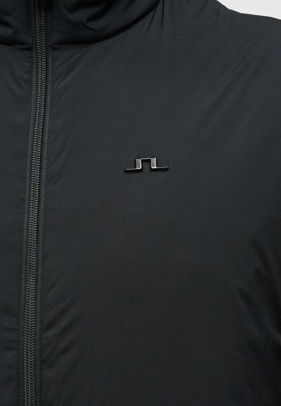 Μαύρο μπουφάν με φερμουάρ, με ματ φινίρισμα, που διαθέτει ένα μικρό, μαύρο, γωνιακό λογότυπο στο αριστερό στήθος.