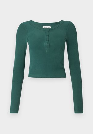 Green long-sleeve ribbed top with a rounded neckline and buttoned placket down the front. Cropped length with a fitted design.