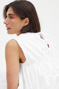 Valge puuvilla kleit, millel on volditud büst, laiad rihmad ja paelad taga. Sujuv tekstuur ja kerge kangas.