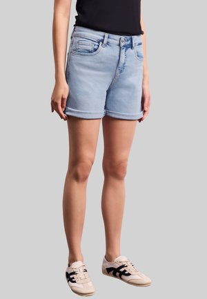Shorts in denim blu chiaro con orlo arrotolato, cinque tasche e chiusura a zip. Abbinati a sneaker bianche e nere.
