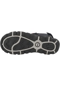 Černá a šedá podešev sportovní obuvi s výraznými vzory, strukturovaným povrchem a centrálním kulatým logem. Obsahuje drážky pro trakci.