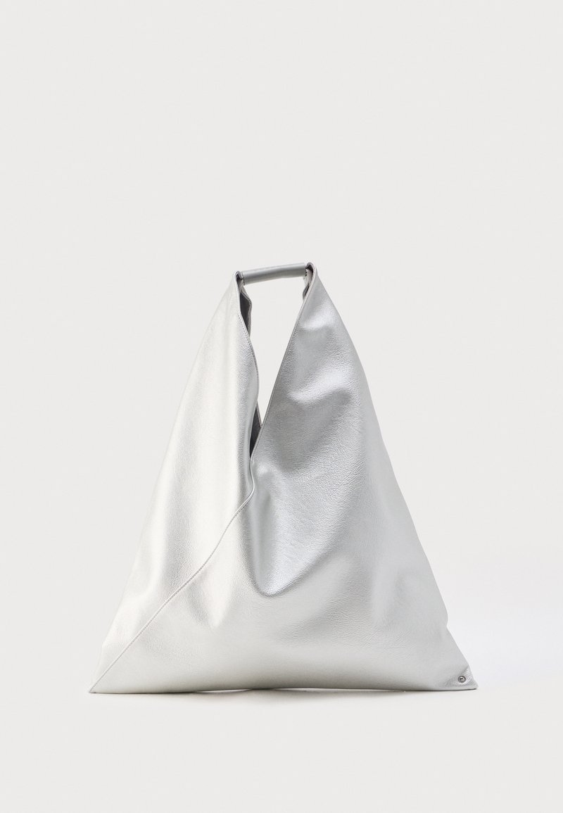 Μεγάλη ασημένια τσάντα ώμου σε τριγωνικό σχήμα με απαλό δερμάτινο υλικό, όρθια με εμφανή την κορυφαία λαβή σε απλό φόντο.