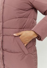 Gepolsterter Mantel in Mauve, mit einer Tasche an der Seite und diagonalen Steppmustern. Glatter, leichter Stoff mit einem lockeren Schnitt.