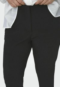 Svarta byxor i ett slätt, matt tyg med en skräddarsydd passform. Har en enkel design, platt front och diskreta sidofickor.