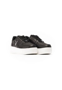 Sneaker in pelle nera con suola platform bianca spessa, dotate di lacci neri e dettagli perforati, impreziosite da un piccolo logo sul lato.