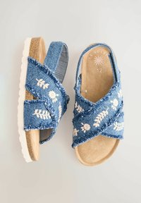 Infradito in denim con fasce incrociate, caratterizzate da ricami floreali bianchi e una suola imbottita beige. Leggeri con tessuto testurizzato.