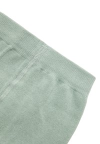 Tejido de punto verde claro con una textura suave, que presenta una cinturilla con canalé. El material parece suave y es ligeramente elástico.