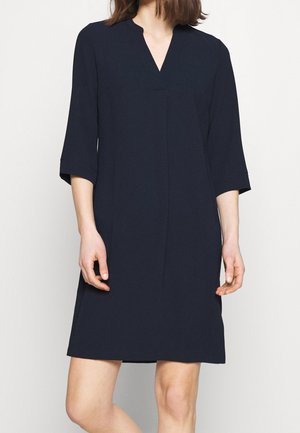 Marineblauwe jurk met een V-hals, driekwartmouwen en een rechte silhouet. Gemaakt van een gladde stof met minimale details.