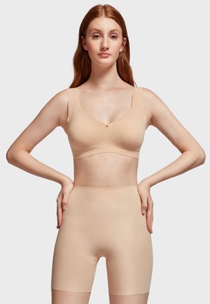 Bralette sans fil beige avec de larges bretelles et une coupe douce, associé à un short sculptant sans coutures taille haute de couleur assortie.