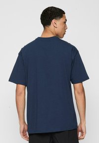 Mørkeblå bomulds t-shirt med en afslappet pasform, korte ærmer og en klassisk rund hals. Glat tekstur, ingen synlige mønstre eller detaljer.