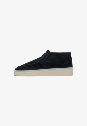 Schwarze Wildleder-Slipper mit runder Spitze, einer weißen Gummisohle, minimalen Nähten und ohne sichtbare Beschläge.