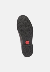 Botín de cuero marrón con una suela de goma negra texturizada que presenta un patrón geométrico, marcado con un logo rojo de "Camper" en el centro.