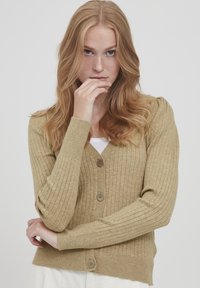 Cardigan beige côtelé avec un col en V, comportant cinq boutons marron, un tissu tricoté texturé et des manches longues ajustées.