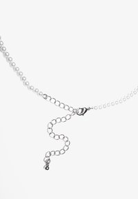Collier en perles blanches avec chaîne en argent, doté d'un fermoir à homard et de maillons ronds. Surface texturée avec finition brillante.
