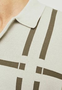 Lys grå polo skjorte med mørkegrønne, vandrette og lodrette striber. Blødt strik med klassisk kravedesign.